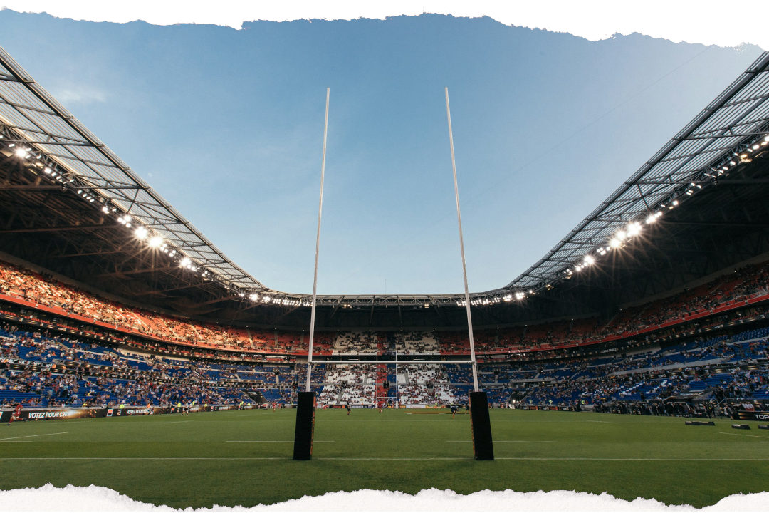 Rugby goalposts in a packed stadium under floodlights