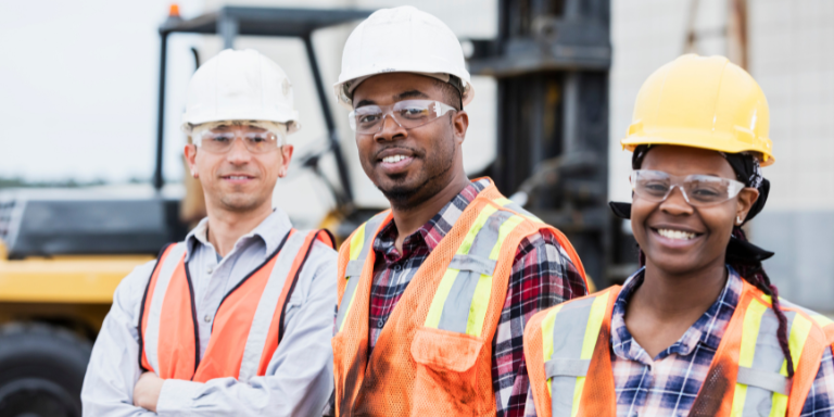 Three people in safety gear at a construction site