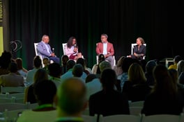 Painel de 4 palestrantes sentados no palco 