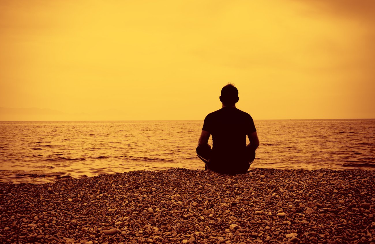 A man sits on the beach overlooking ocean