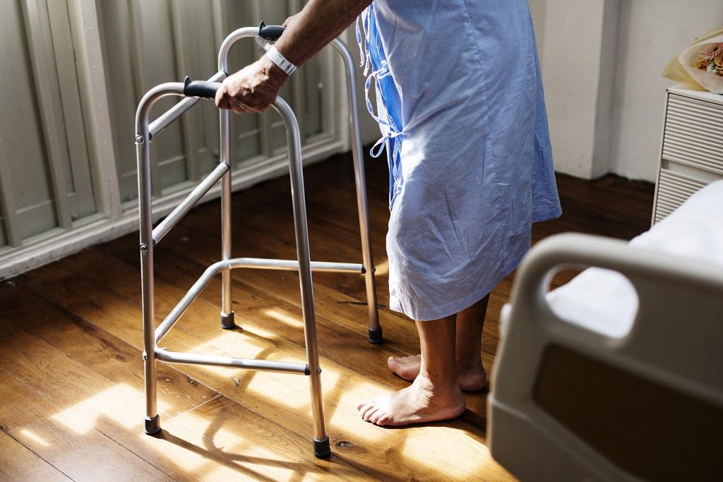 Photo of a hospital patient holding onto a walker