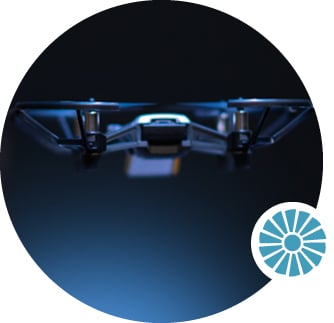 A close-up of a drone flying on a dark background.