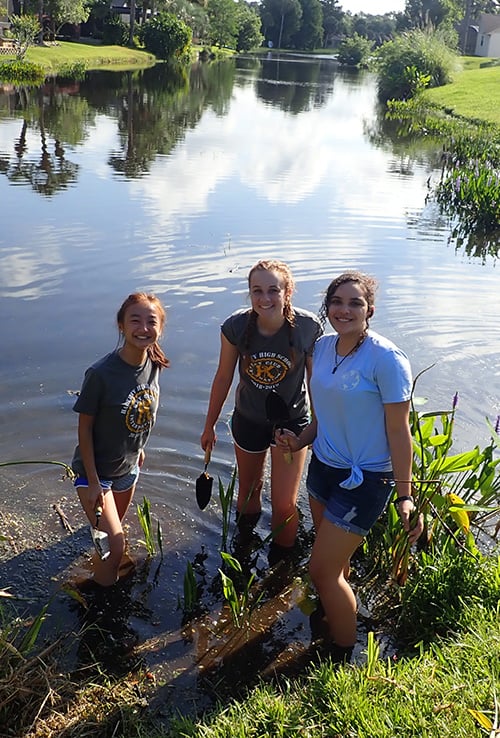 three girls volunteering standing in sweetwater lake