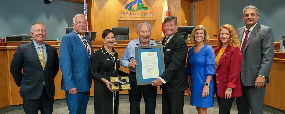 Lee Corso holding his Proclamation along with The Board of County Commissioners, Darren Grey County Manager, and Kate Latorre County Attorney