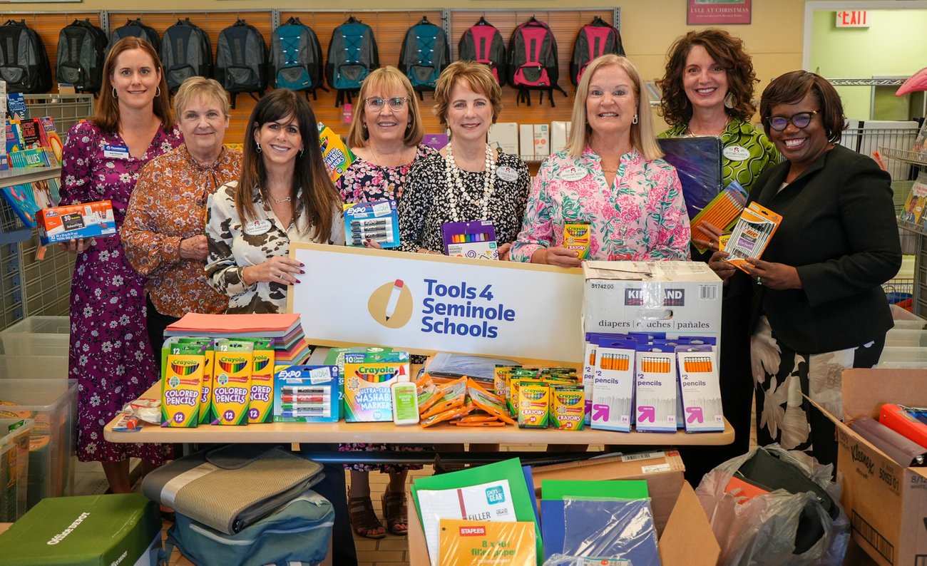 School Board members standing with Staff behind of donated school supplies
