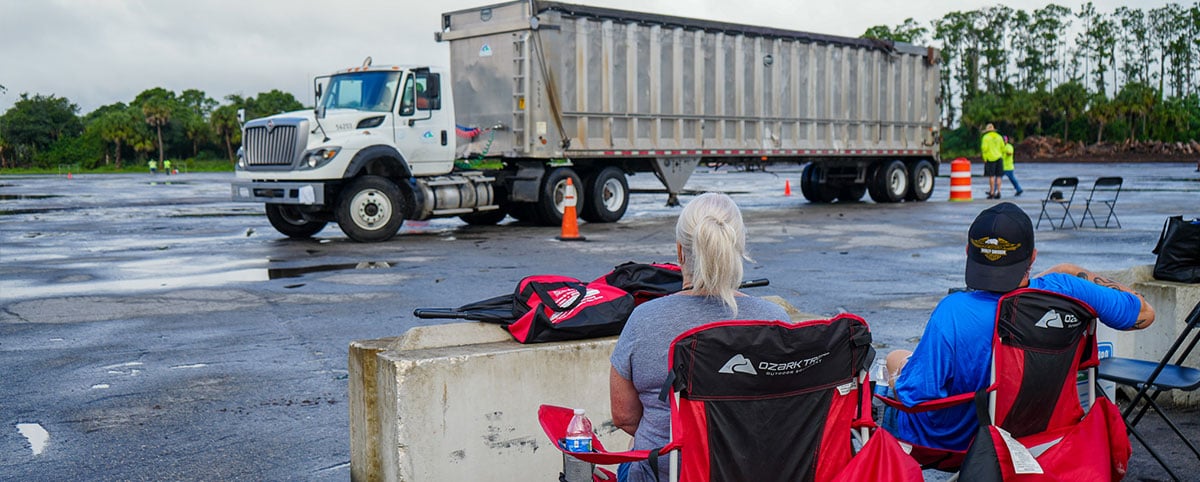 Spectators watching a truck perform skills competition at landfill