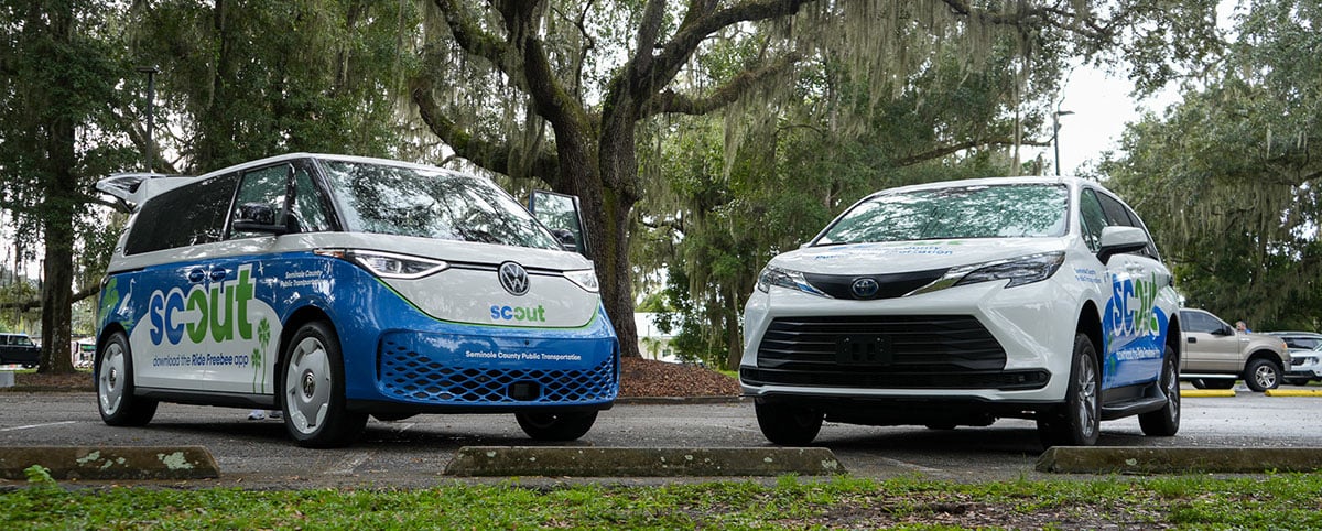 SCOUT microtransit vehicles parked under a cypress tree