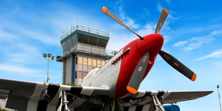 Photo of a propeller
airplane in front of a control tower at the Hayward Executive Airport.