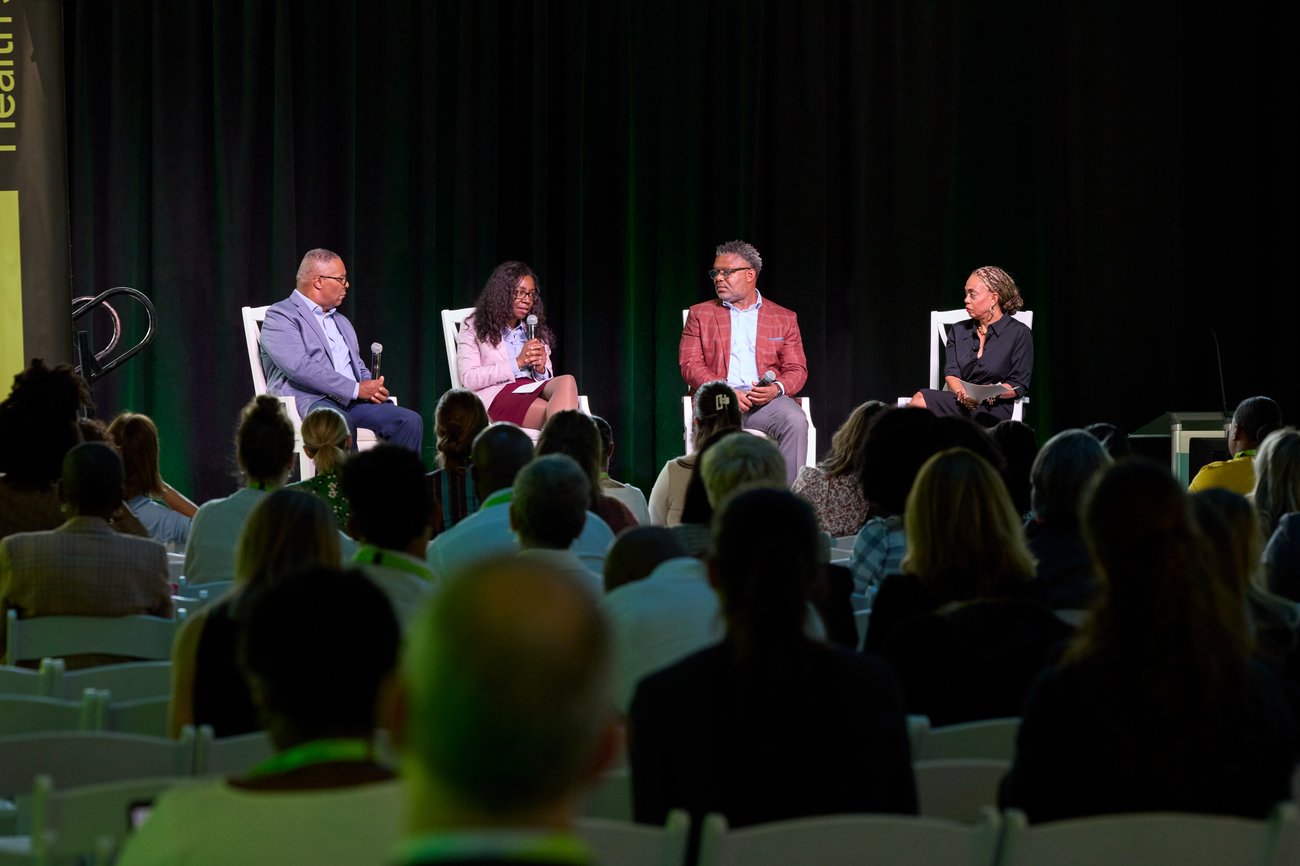 Painel de 4 palestrantes sentados no palco 