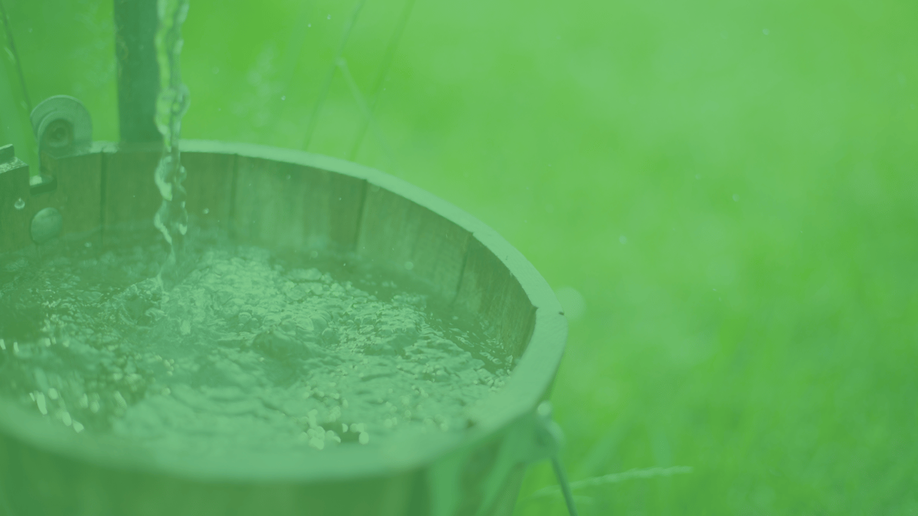 A bucket collecting well water in a field.