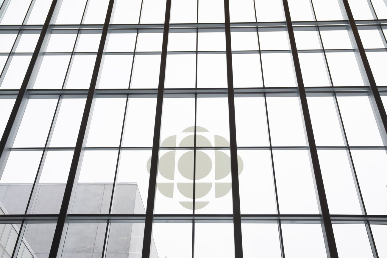 A photograph of windows with black panes and white interiors. The CBC logo is near the centre.