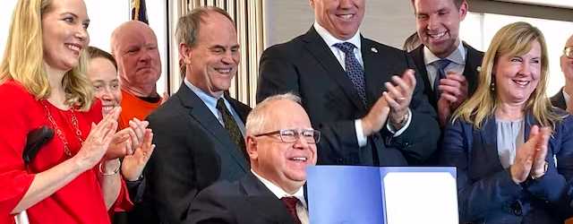 Governor Walz displays a bill he signed into law requiring Minnesota utilities to get 100 percent of their electricity from carbon-free sources by 2040. AP/Steve Karnowski