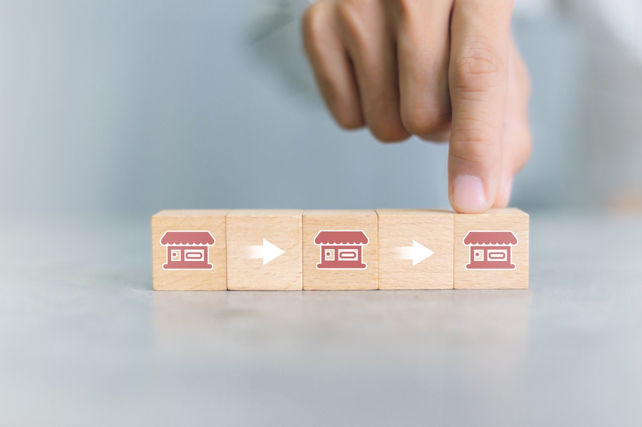 hand holding one of three wooden boxes with franchise icon on them