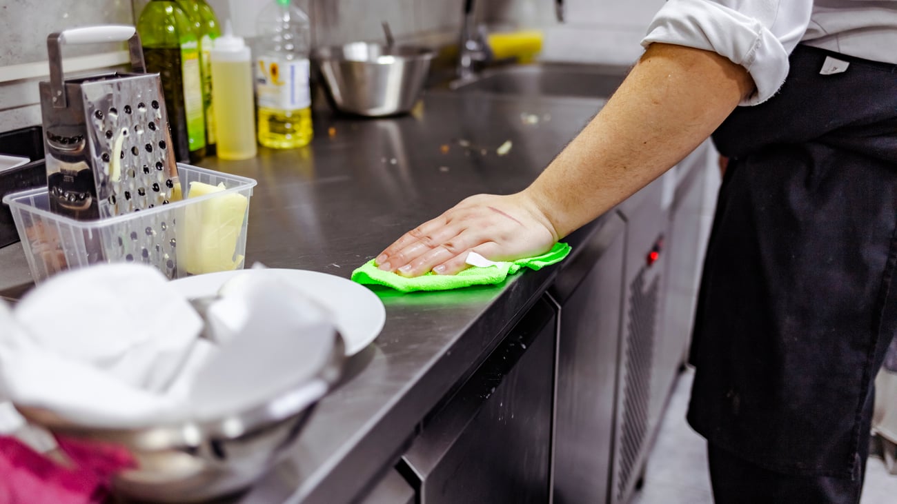 chef cleaning up a workstation in back of house restaurant