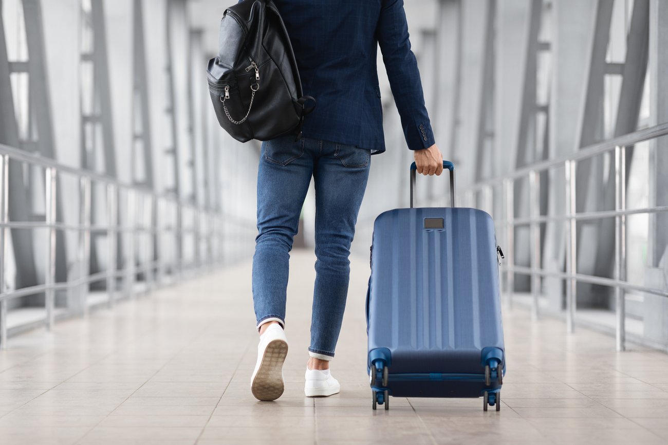 businessman walking through an airport with a backpack and luggage