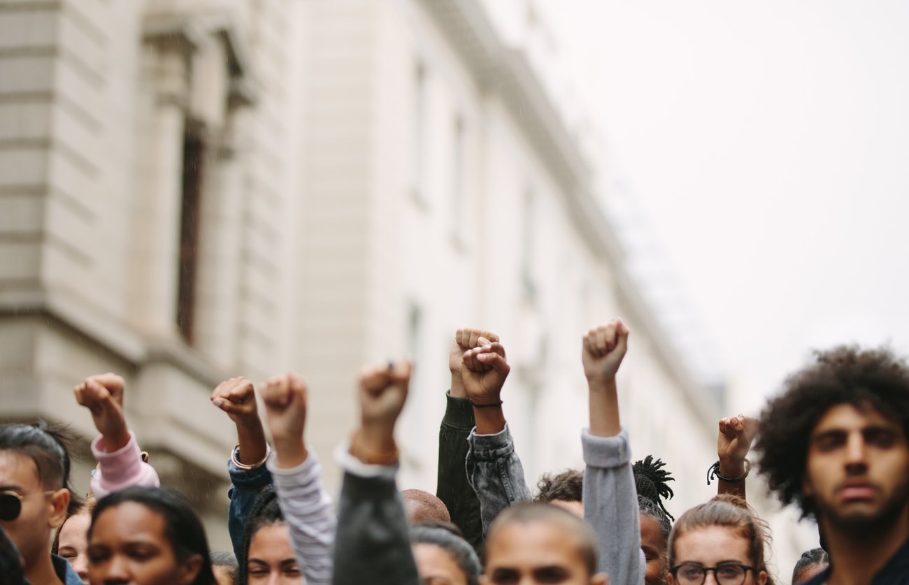 diverse group of people, some with their arms raised in protest