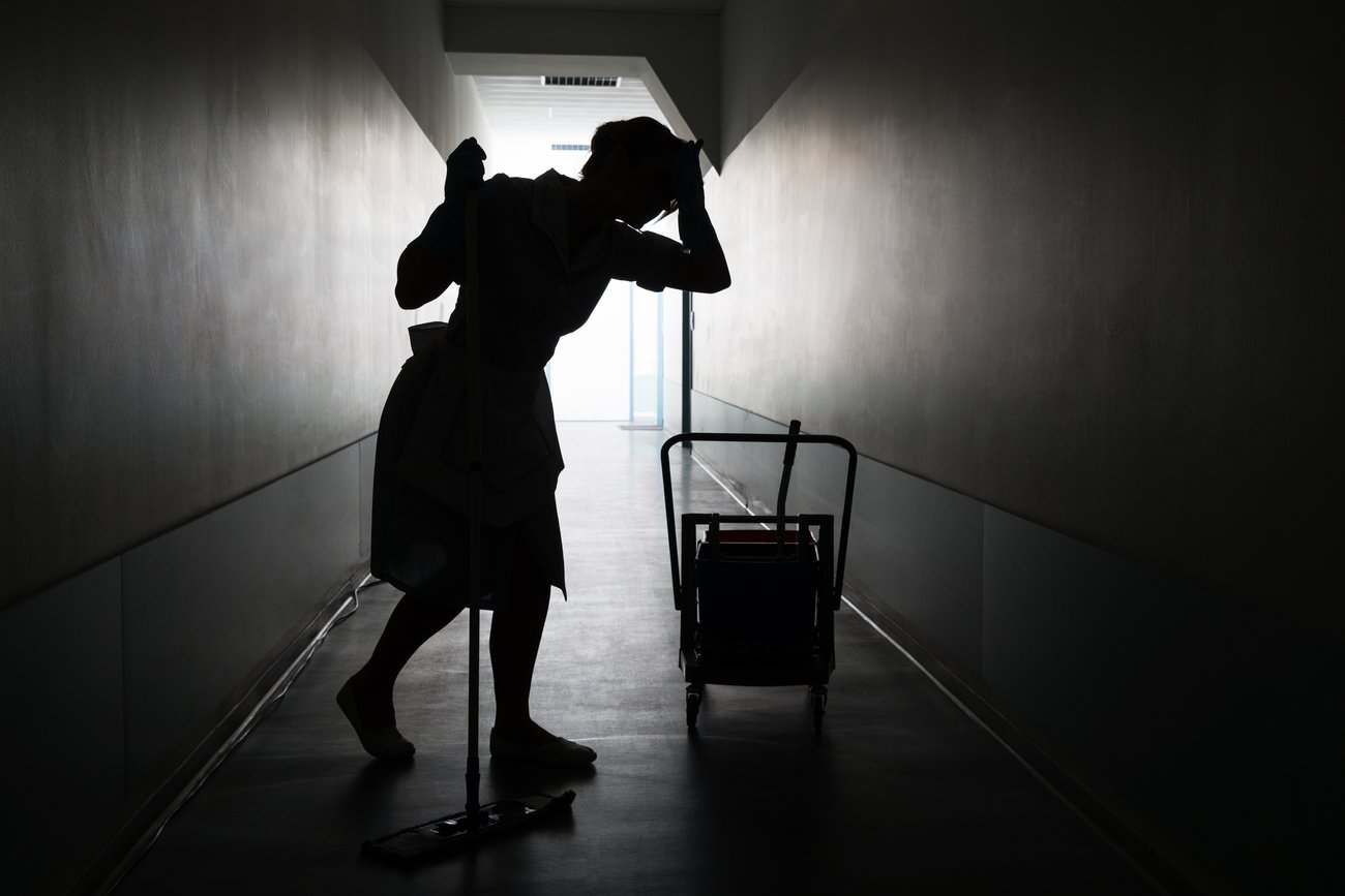 silhouette of a female housekeeper with a mop and bucket in a hallway