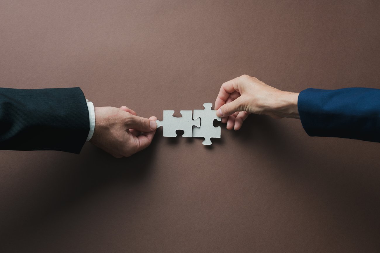 two businessmen connecting two puzzle pieces together