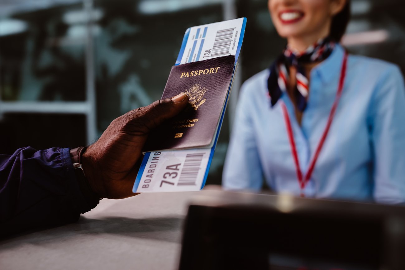 man handing a passport and flight ticket to check in counter at an airport