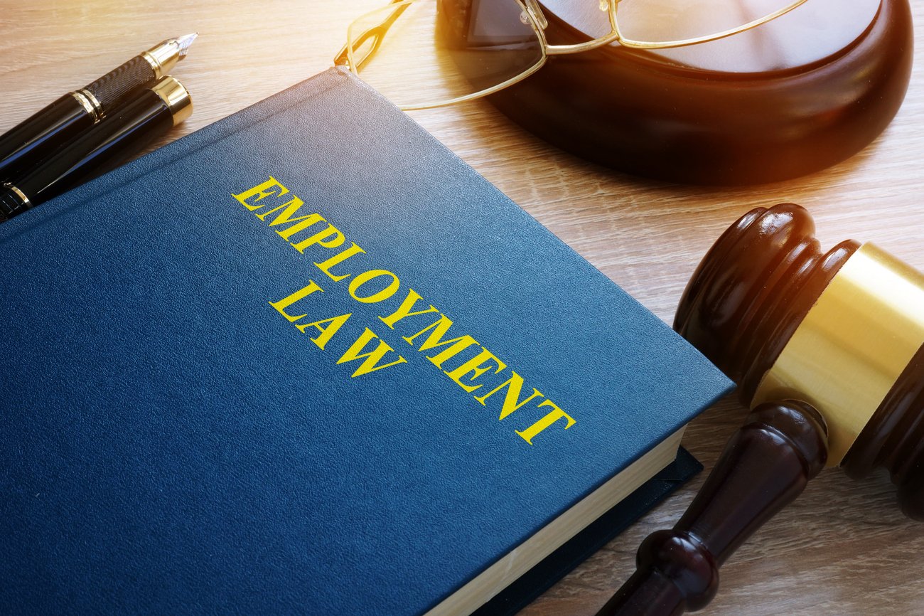 book titled employment law next to a judge's gavel, pens, and glasses