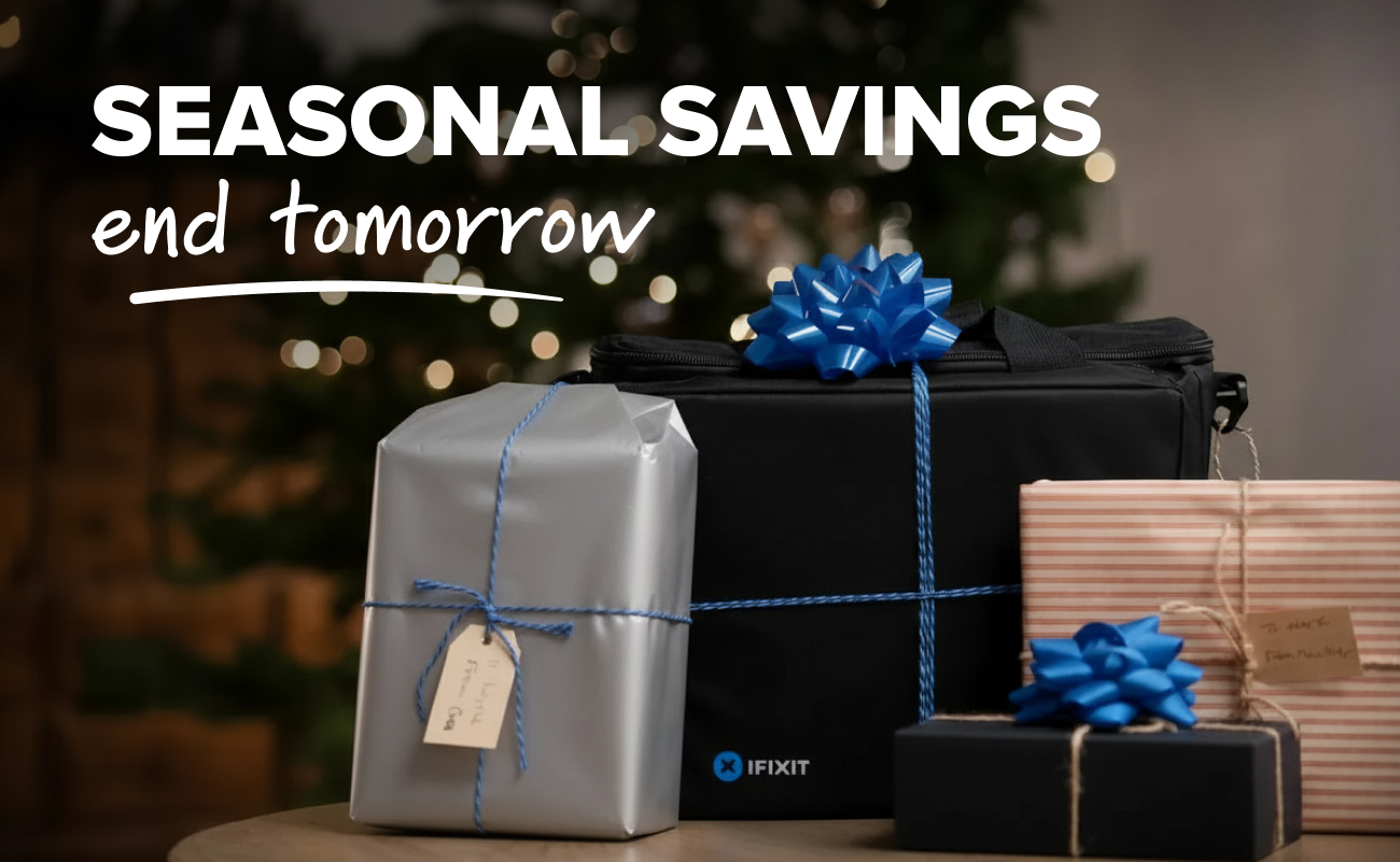 Ambient lifestyle image showing a stack of wrapped holiday gifts arranged around Repair Business Toolkit bag decorated with a blue bow, set in front of a softly lit Christmas tree with warm bokeh lights.