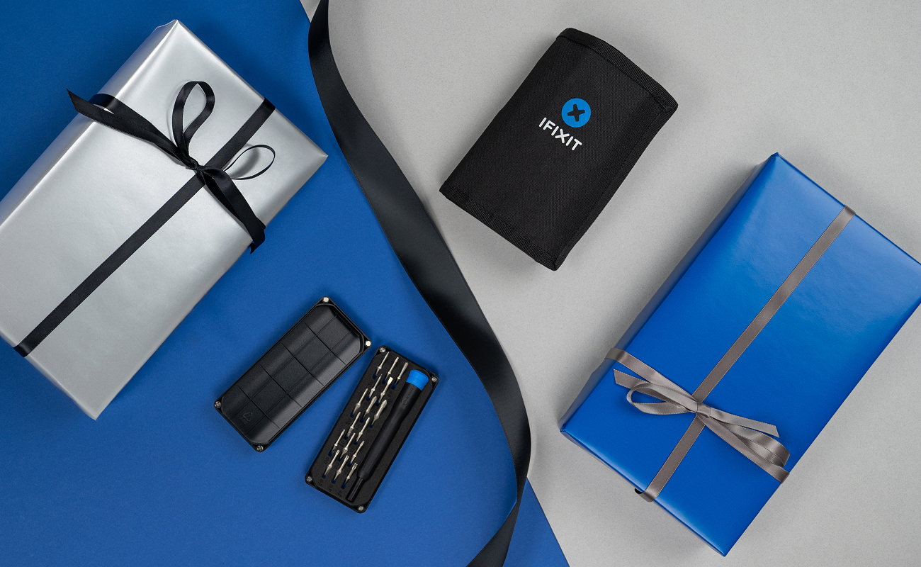 Product image showing the Minnow Driver Kit opened to reveal precision bits and driver, arranged between blue- and silver-wrapped gifts and the closed Pro Tech Go Toolkit on a split blue and light-grey background.