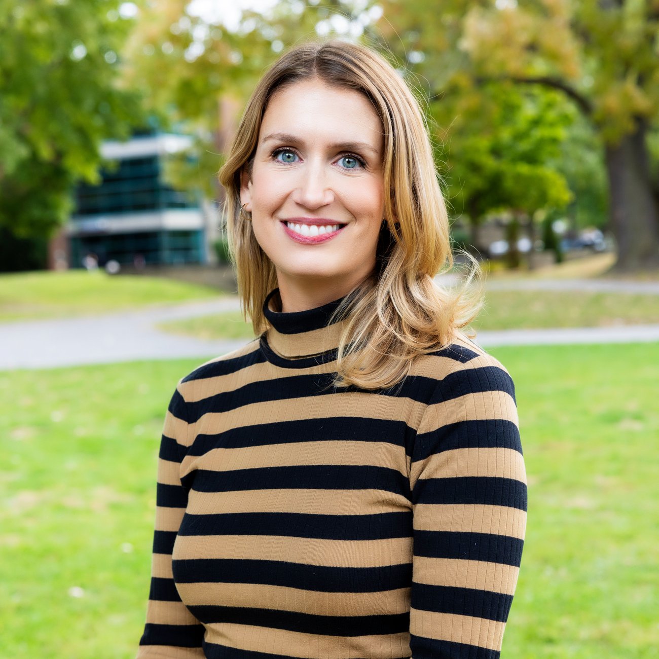 lady smiling, wearing a brown and black strip top