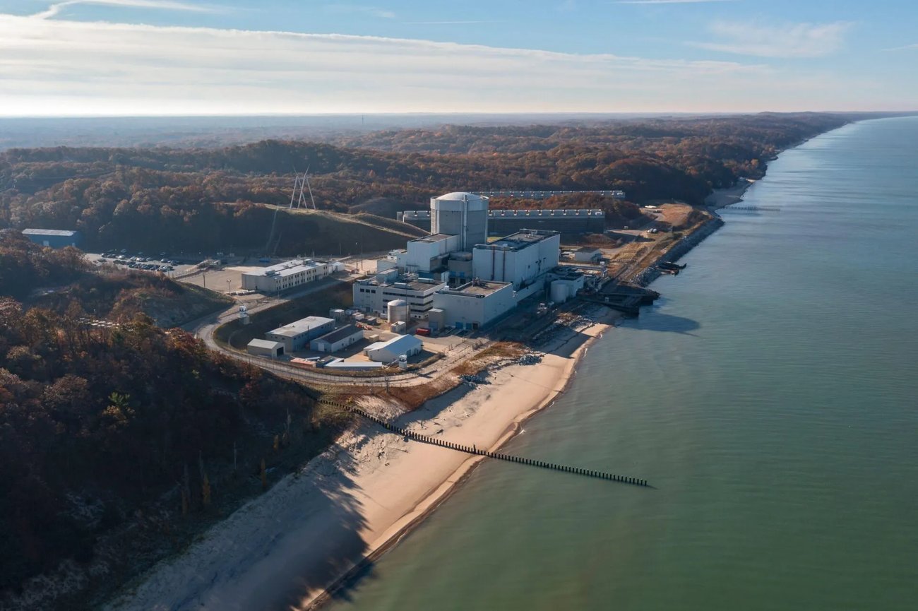 The Palisades nuclear power plant a white industrial building on the shore of Lake Michigan The land around the plant is forested