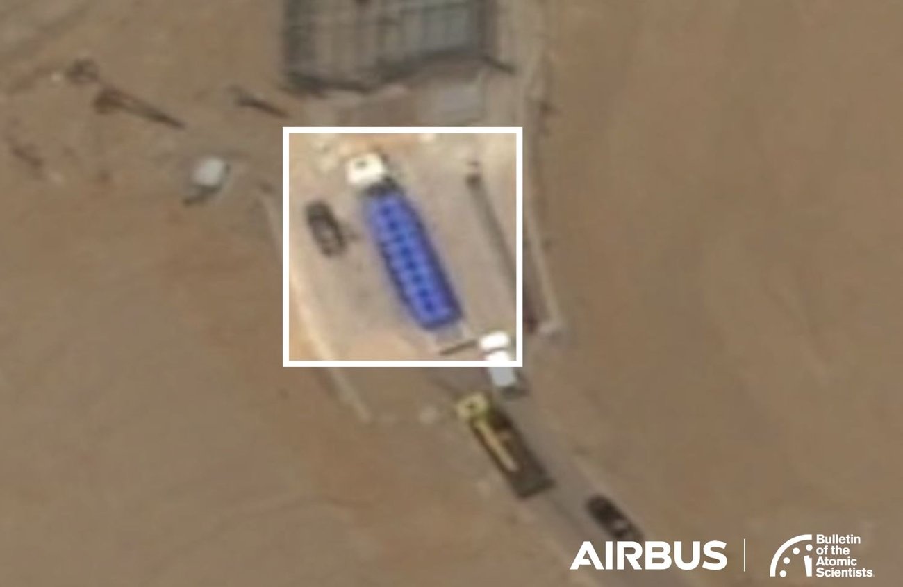 An image from above shows a desert landscape with a few trucks on a road A white box highlights a large flatbed truck with a blue container
