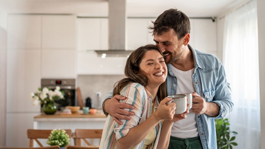 Smiling and hugging couple with coffee in their hands