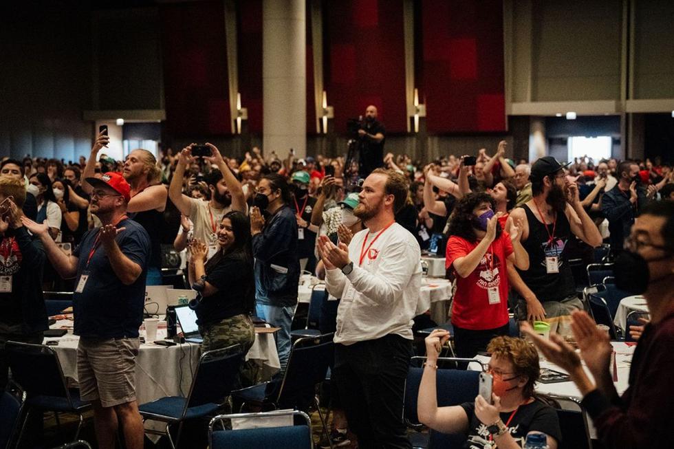 Hundreds of people are standing, clapping, and taking pictures at the DSA Convention.