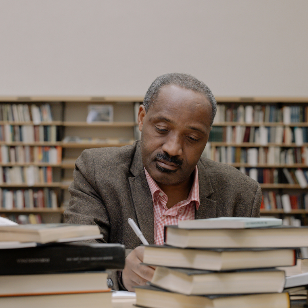 A person writes, surrounded by books in a bright library. A person writes, surrounded by books in a bright library.