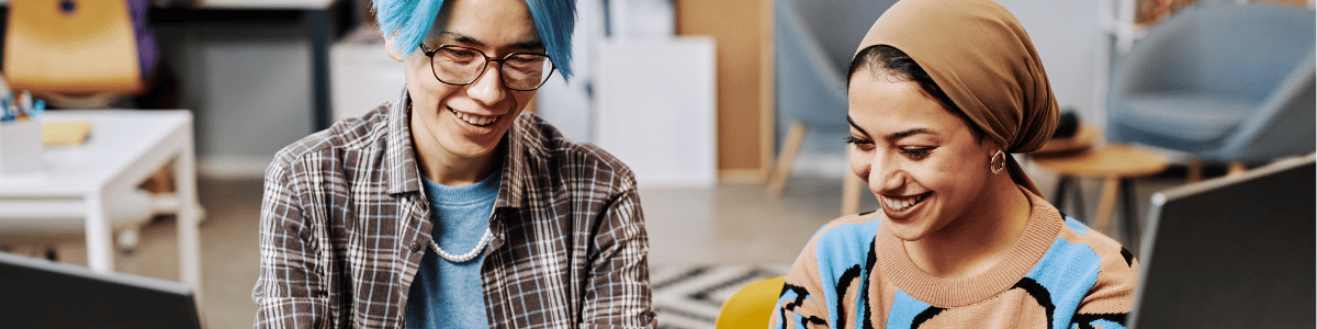 Two people smiling while working on shared computers.