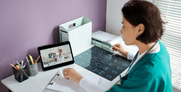 Nurse watching a zoom call of medical professional viewing an xray