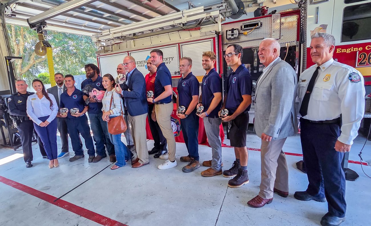 Employees posing with awards and Fire Chief Matt Kinley in front of fire engine at station.