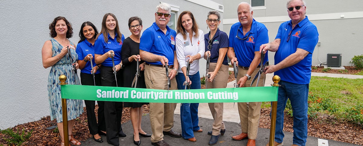 Ribbon cutting ceremony with Commissioner Herr and employees from Central Florida's Home for Good in front of an apartment complex.