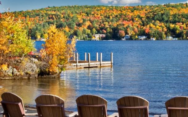 fall foliage on lake, adirondack chairs in foreground
