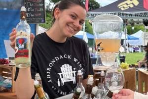 woman at festival booth holds up bottle of wine