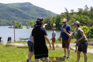 people playing lawn games with water and mountains in background
