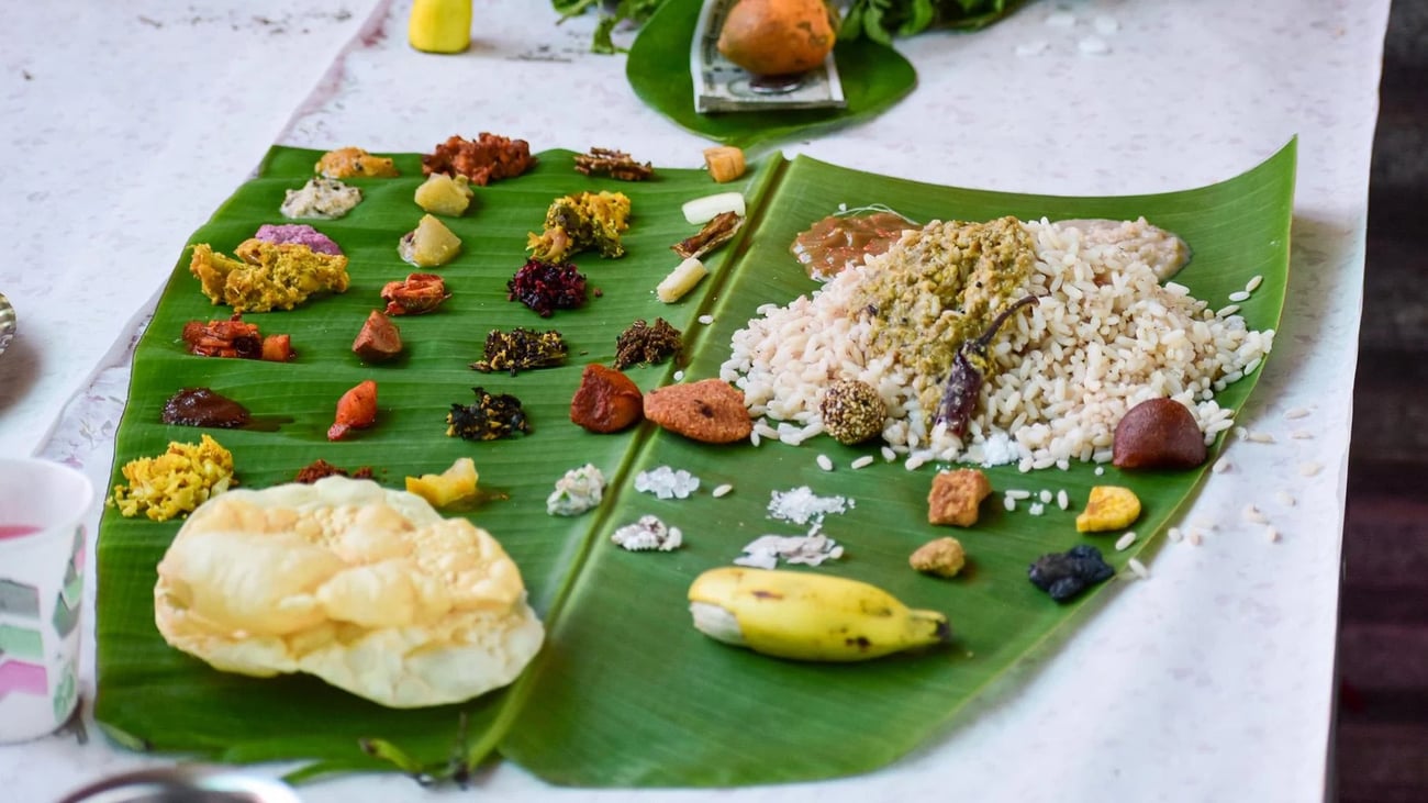 A variety of Indian foods, a banana, and rice laid out on a banana leaf