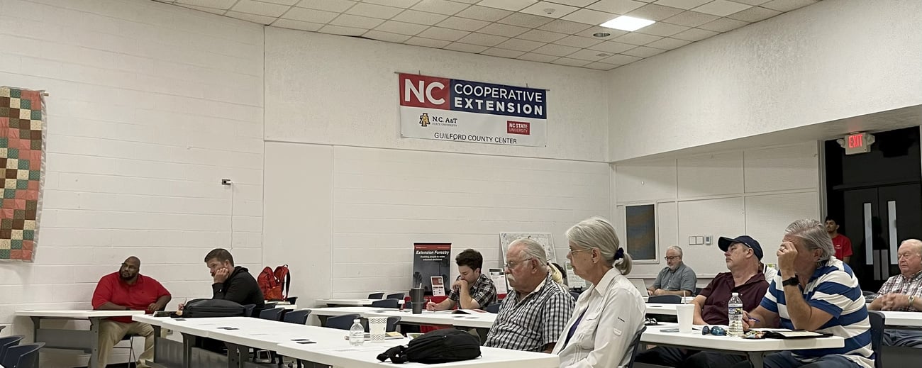 Photo from NC Cooperative Extension Guilford County Center Open House. People conversing and visiting information tables in the lobby. 
