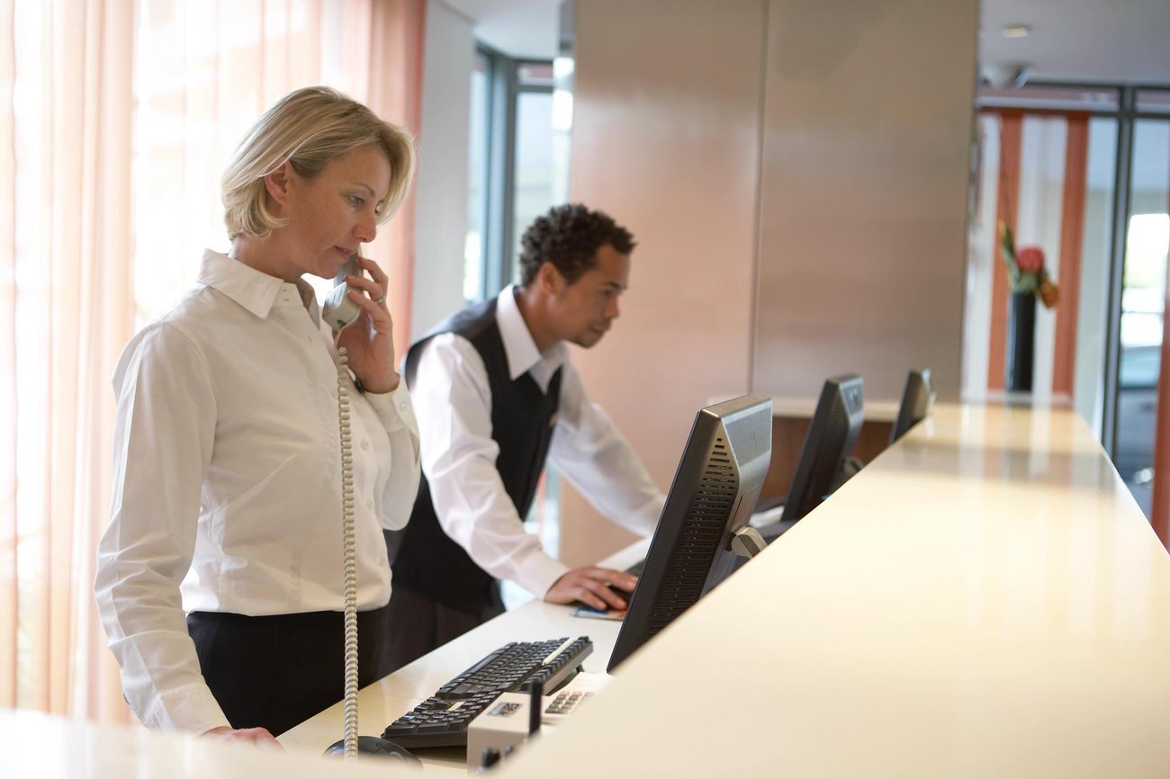 Hotel workers looking at computers at front desk
