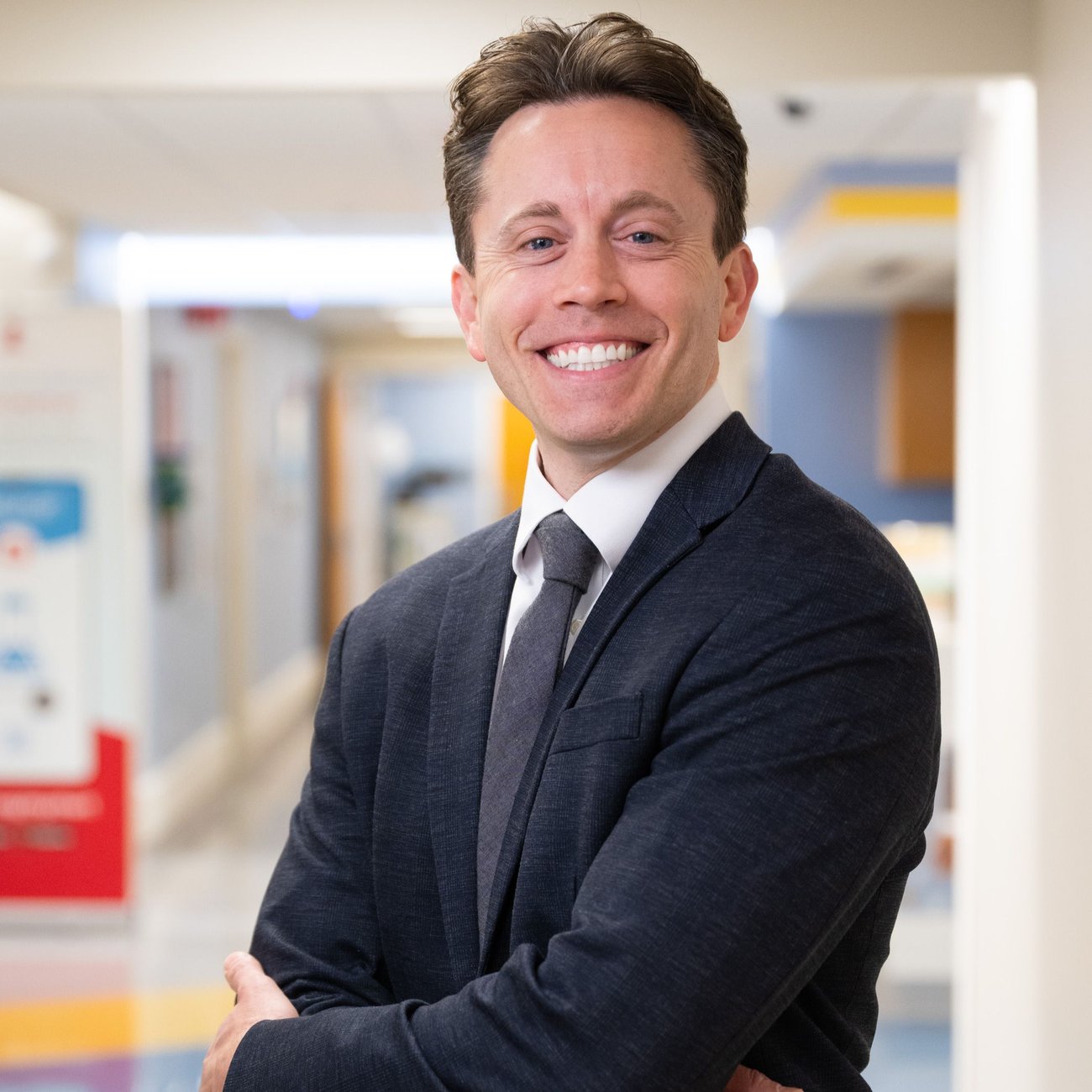A man smiling with a suit and tie on