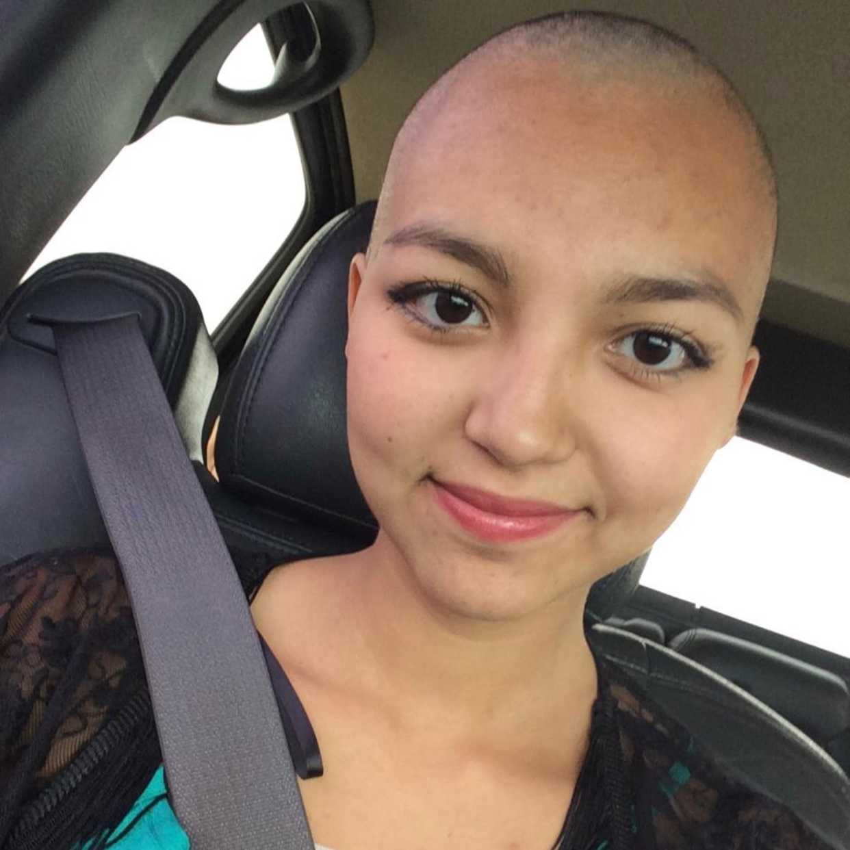 young lady smiling, wearing a black shirt in a car