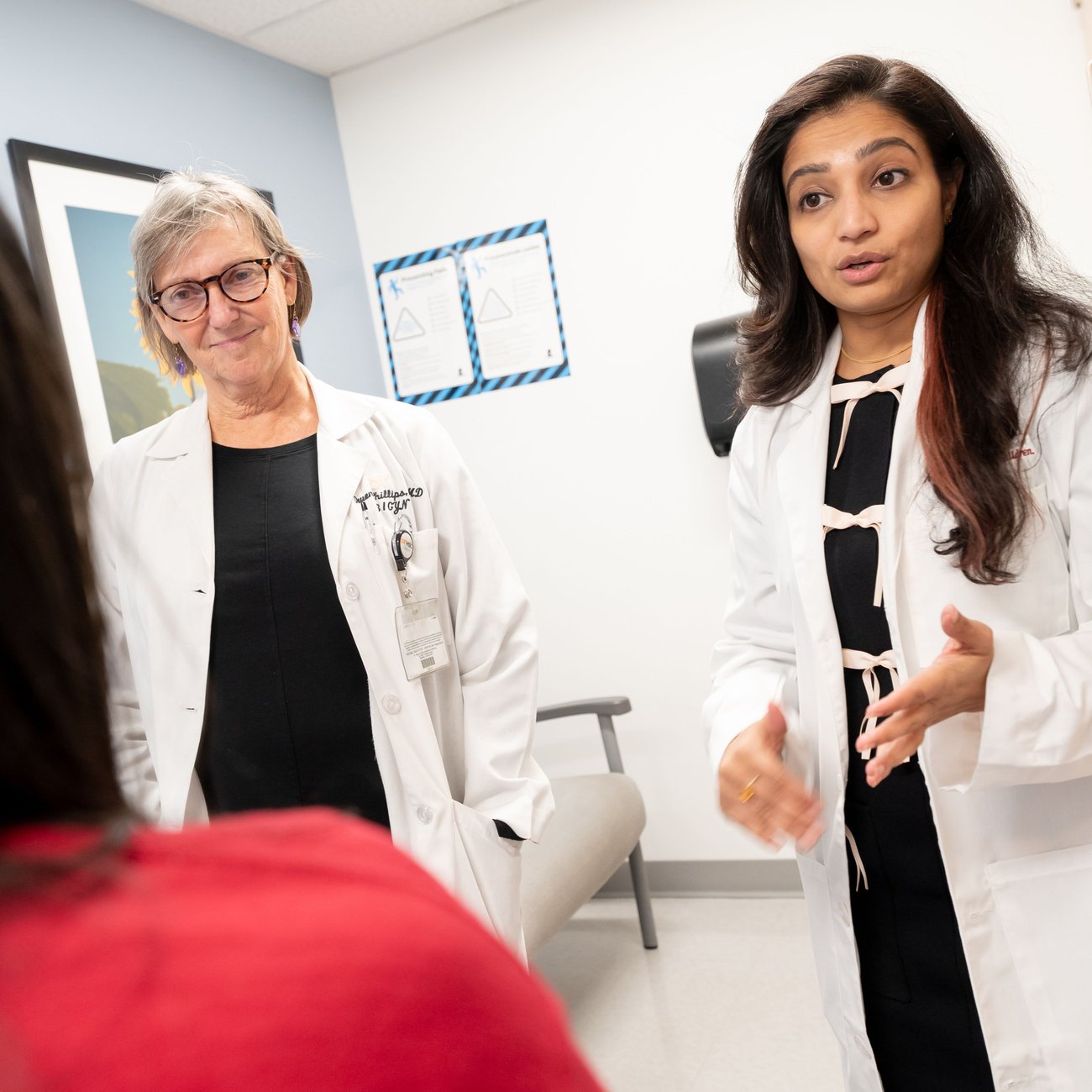 Image of two women in white coats talking while in a medical setting