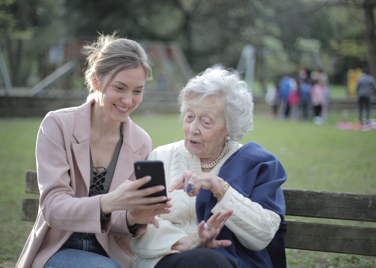 Vrouwen met smartphone op bankje