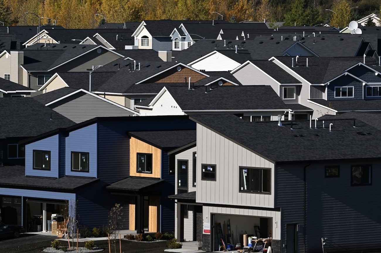 Rows of modern suburban homes with dark roofs and autumn trees