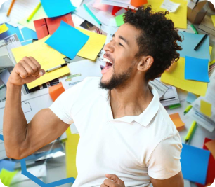 Joyful man raising a fist amid colorful papers and sticky notes