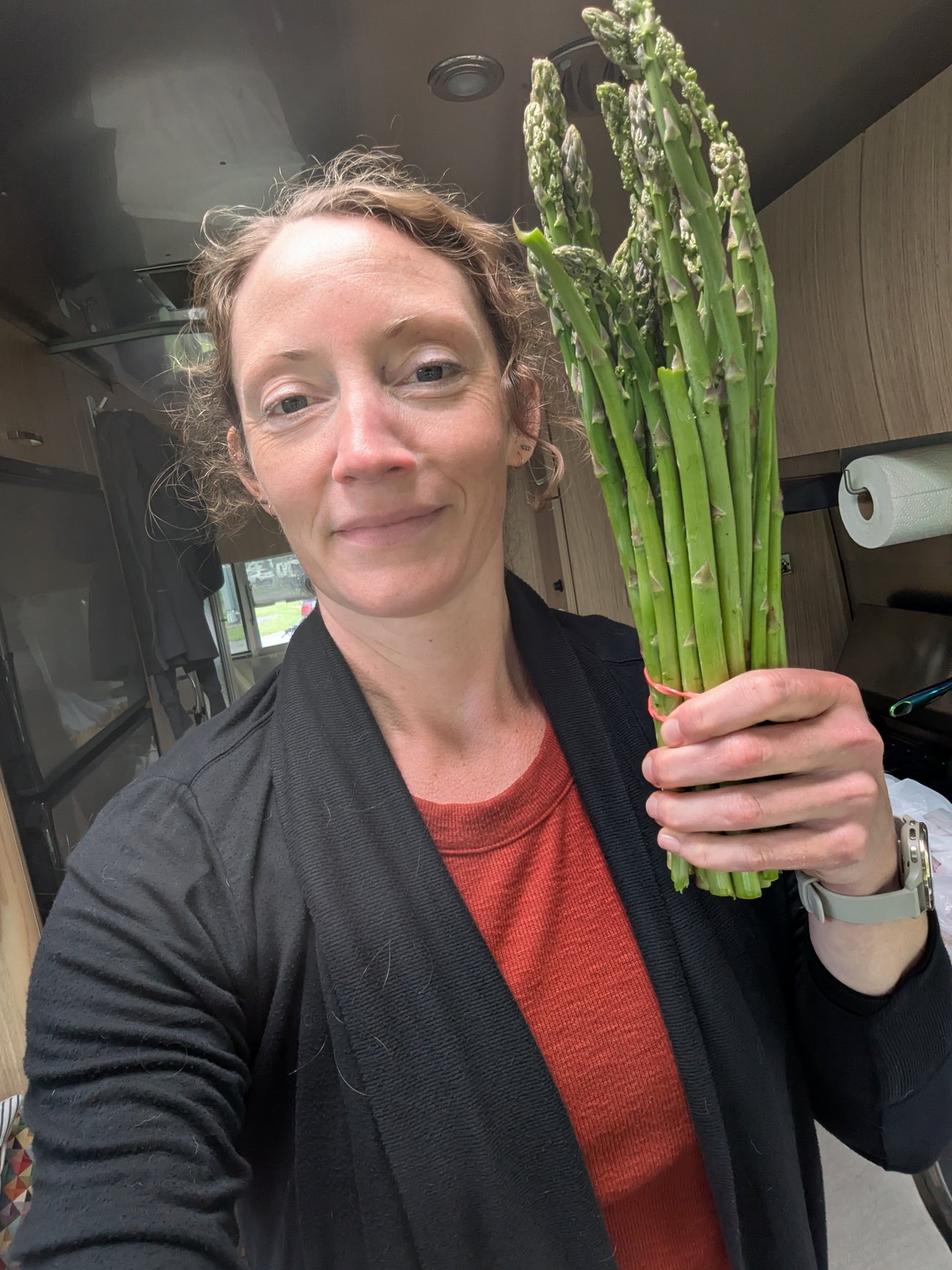 Abby holding a fresh bunch of asparagus inside an Airstream kitchen.