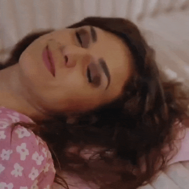 A woman with dark hair sleeping on pink floral bedding